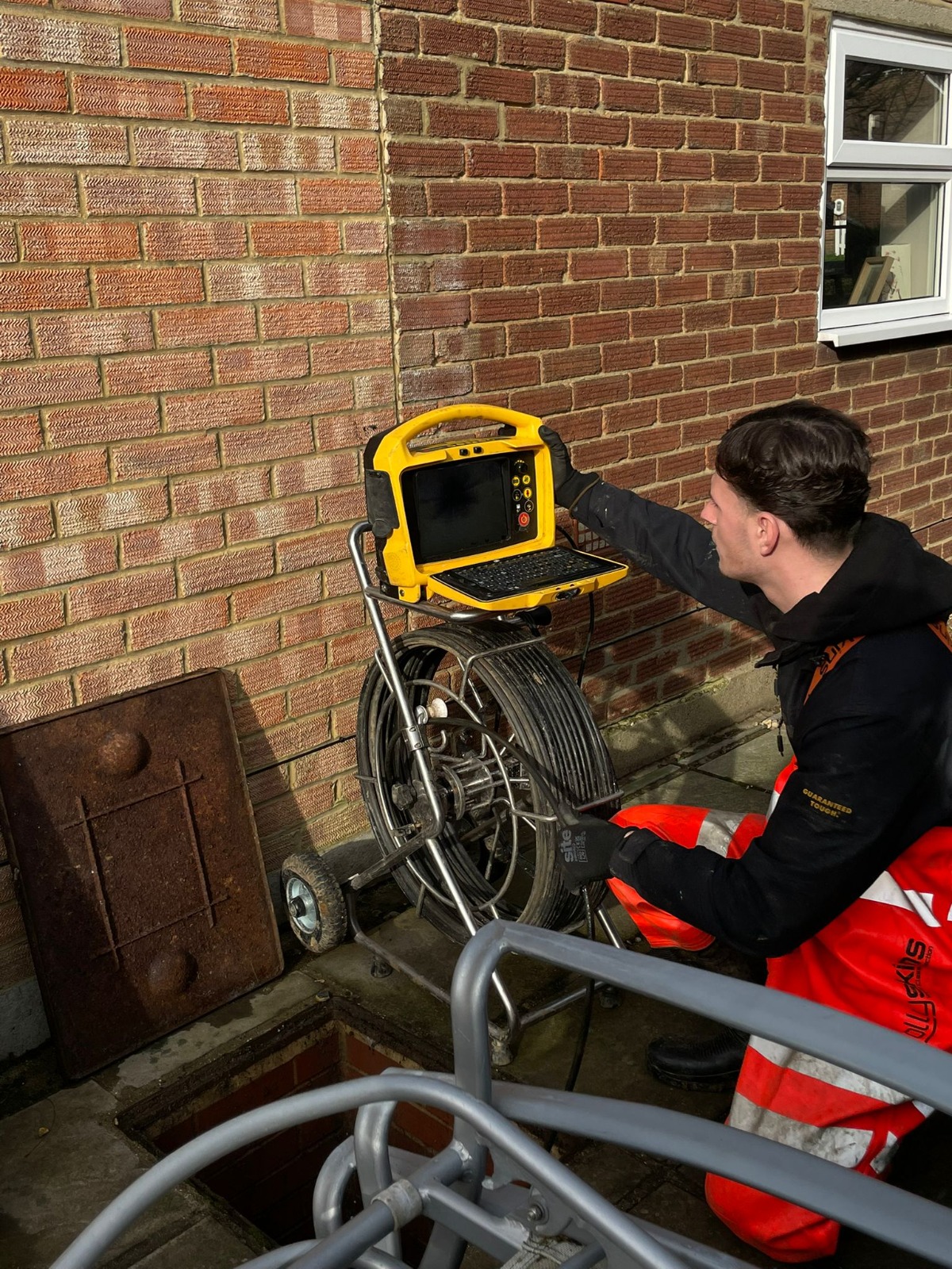 Push-rod CCTV drain camera reel and monitor recording footage at an open manhole